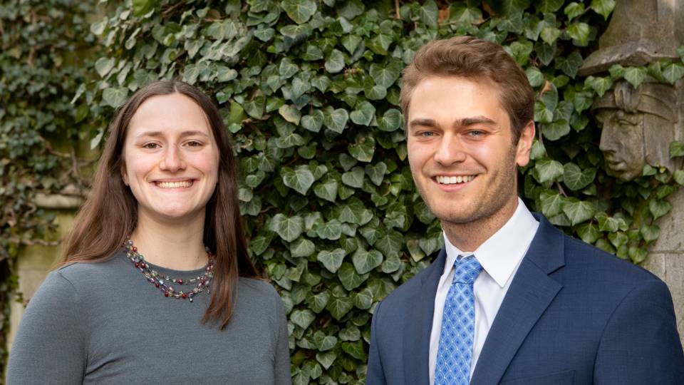 A female and male student in front of ivy